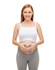 Image showing happy future mother showing heart with her hands
