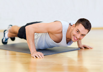 Image showing smiling man doing push-ups in the gym