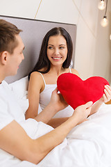 Image showing smiling couple in bed with red heart shape pillow