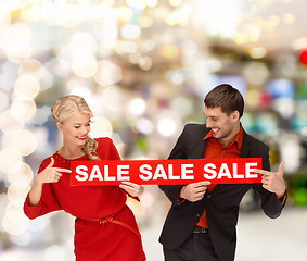 Image showing woman and man pointing finger to red sale sign