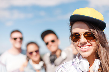 Image showing teenage girl with headphones and friends outside