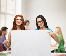 Image showing two smiling girls with eyeglasses and blank board