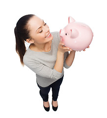 Image showing happy woman looking at piggy bank
