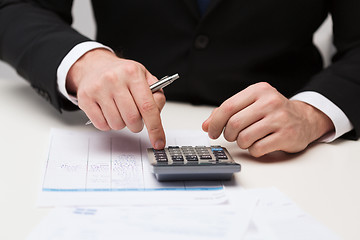 Image showing close up of businessman with papers and calculator