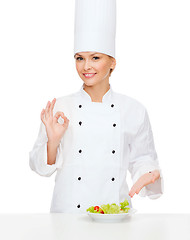 Image showing smiling female chef with salad on plate