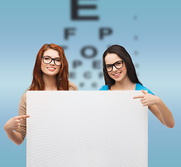 Image showing two smiling girls with eyeglasses and blank board
