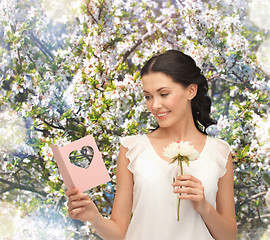 Image showing young woman holding flower and postcard