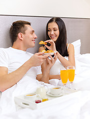 Image showing smiling couple having breakfast in bed in hotel