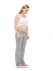 Image showing happy pregnant woman weighting herself