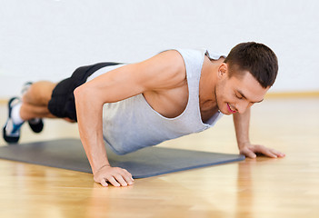 Image showing smiling man doing push-ups in the gym