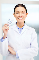 Image showing smiling young doctor in cabinet with pills