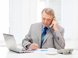 Image showing busy older businessman with laptop and telephone