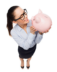 Image showing happy businesswoman in eyeglasses with piggy bank