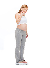 Image showing amazed pregnant woman weighting herself