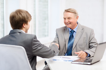 Image showing older man and young man shaking hands in office