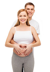 Image showing happy young family expecting child with heart