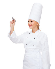 Image showing smiling female chef writing something on air