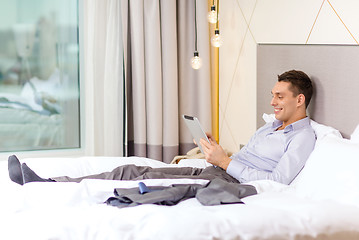 Image showing happy businesswoman with tablet pc in hotel room
