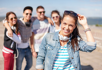 Image showing teenage girl with headphones and friends outside