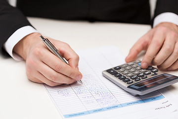 Image showing close up of businessman with papers and calculator