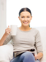 Image showing woman with cup of coffee reading magazine at home