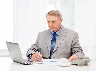 Image showing busy older businessman with laptop and telephone