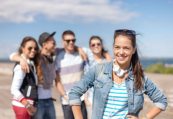 Image showing teenage girl with headphones and friends outside