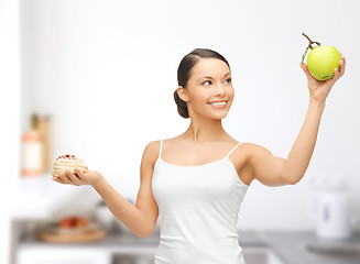 Image showing sporty woman with apple and cake in kitchen