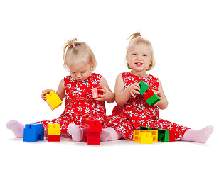 Image showing two twin girls in red dresses playing with blocks