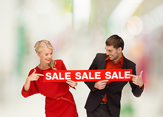 Image showing woman and man pointing finger to red sale sign