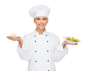 Image showing smiling female chef with salad and cake on plates