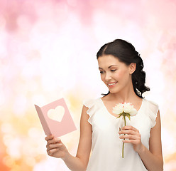 Image showing young woman holding flower and postcard