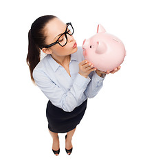 Image showing happy businesswoman in eyeglasses with piggy bank