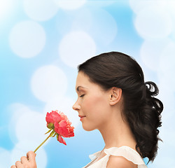 Image showing smiling woman smelling flower