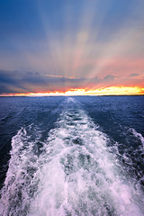 Image showing Sunset over ocean with boat wake