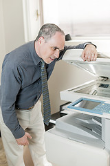 Image showing Man having problem with photocopier in office