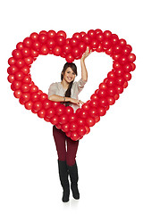 Image showing Smiling woman holding red balloon heart