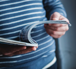 Image showing A man looks at a magazine. Press hands.