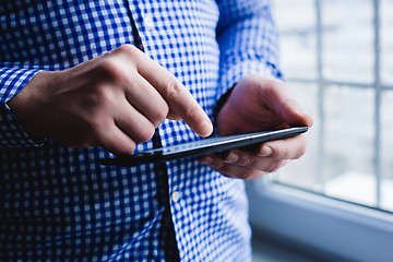 Image showing The man uses a tablet PC. Modern gadget in hand.