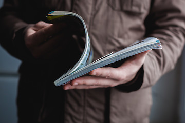 Image showing A man looks at a magazine. Press hands.