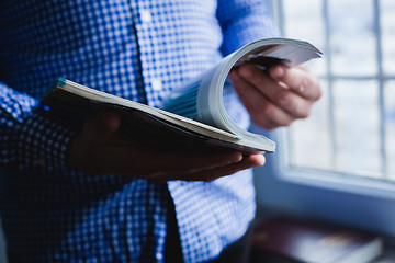 Image showing A man looks at a magazine. Press hands.