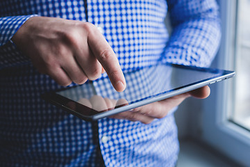 Image showing The man uses a tablet PC. Modern gadget in hand.