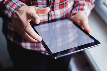 Image showing The man uses a tablet PC. Modern gadget in hand.