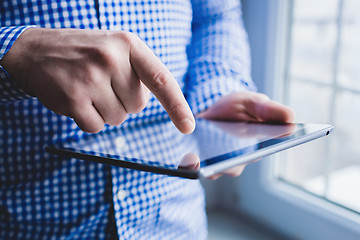 Image showing The man uses a tablet PC. Modern gadget in hand.