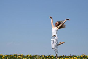 Image showing Smiling girl dancing in dandelion field