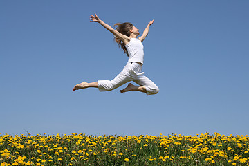 Image showing Girl flying in a jump over dandelion field