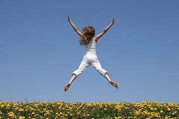 Image showing Girl flying in a funny jump over dandelion field