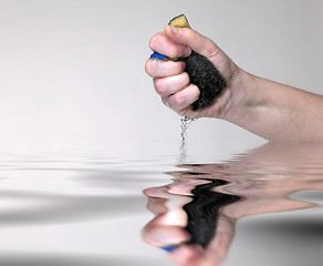 Image showing hand pressing a wet sponge