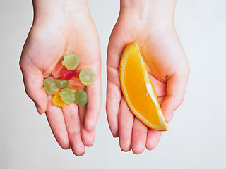 Image showing Candies and orange slice in the hands of a child