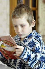 Image showing The 10-year-old boy sits with the textbook, doing homework.